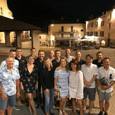 Group of cyclists from Velo Tours standing together smiling for camera in main piazza of Bormio after dinner