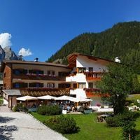View of Swiss style chalet accommodation in Corvara Dolomites Italy that Velo Tours use with green mountains in background
